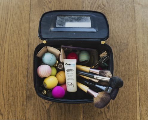 Makeup bag filled with various items, including brushes and Calmmé anti-chafe and soothing cream.