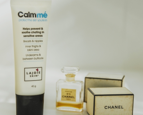 Calmmé anti-chafe and soothing cream tube sitting beside a vintage bottle of Chanel No 5