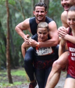 Daphne Kapetas piggybacking her trainer on her back in a mud run